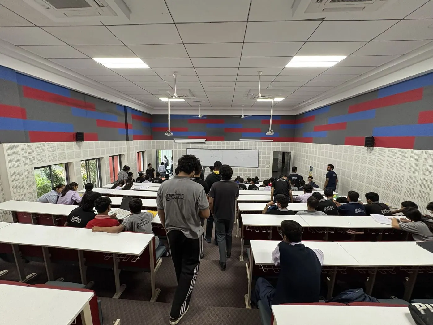 Students in a lecture hall at GEHU with red and blue wall panels